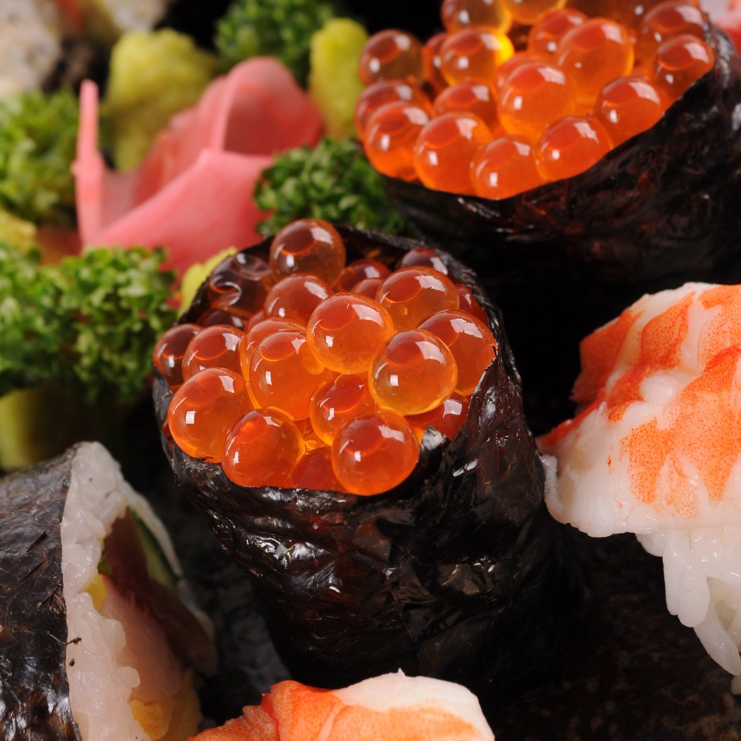 An enticing close-up of vibrant sushi topped with fresh roe, seaweed-wrapped delights, and colourful garnishes of pink pickled ginger and green parsley, showcasing a variety of textures and flavors that bring luxury to the plate.