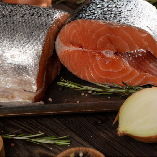 Close-up of fresh Norwegian Fjord Trout slices on a tray with rosemary and onion for garnish.