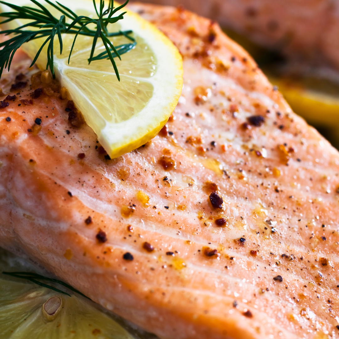 Close-up of grilled salmon trout topped with lemon slice and herbs, showing a seasoned and cooked salmon portion.