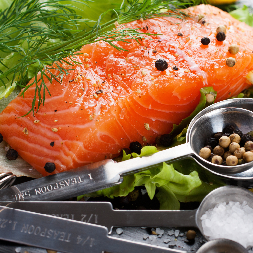 Sashimi-grade Norwegian Fjord Trout slice garnished with dill and black pepper, presented with a fresh salad and seasoning tools.