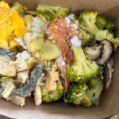 Assorted vegetables including broccoli, mushrooms, and shrimp in a cardboard container.
