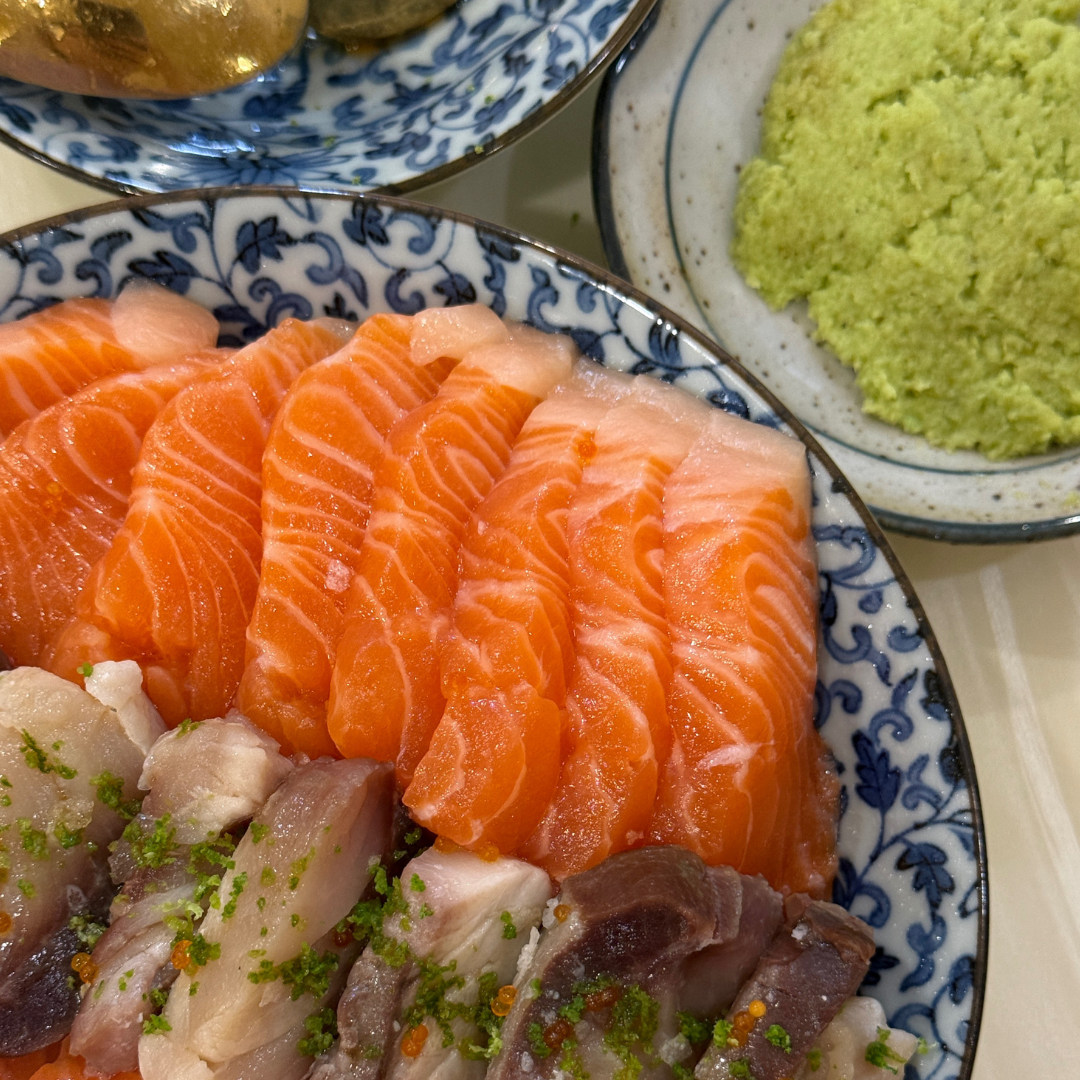 Japanese donburi bowl with salmon sashimi and white fish slices, served with grated wasabi and traditional plateware