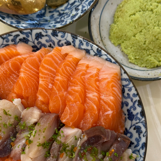 Japanese donburi bowl with salmon sashimi and white fish slices, served with grated wasabi and traditional plateware